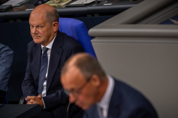 ARCHIV - 11.09.2024, Berlin: Bundeskanzler Olaf Scholz (SPD), schaut zu Friedrich Merz, CDU Bundesvorsitzender und CDU/CSU Fraktionsvorsitzender im Bundestag, in der Generaldebatte zum Bundeshaushalt  ...