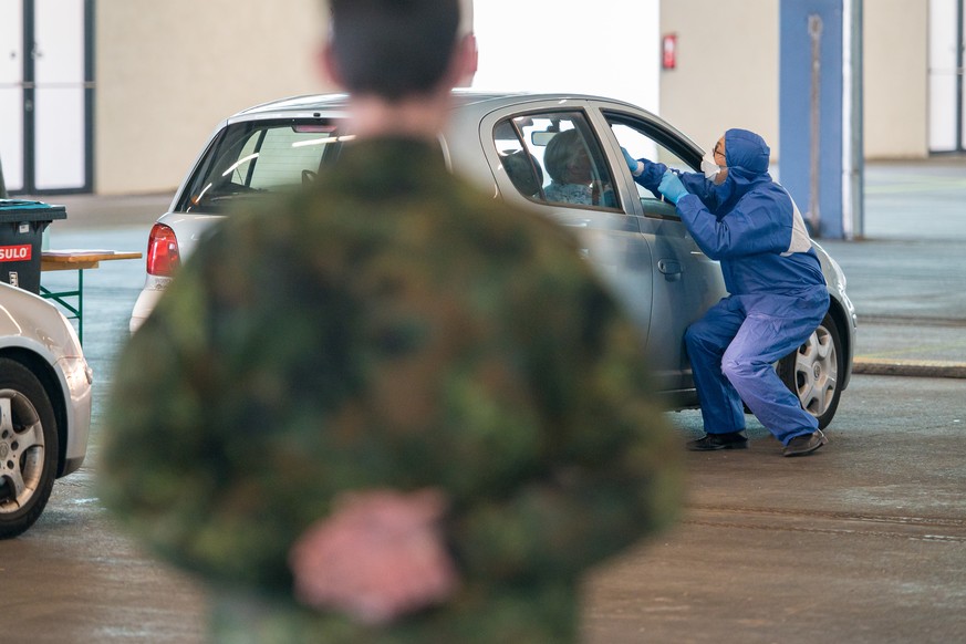 Ein Arzt nimmt bei der von der Bundeswehr organisierten Drive-In Teststation in einer Halle der ehemaligen Saarbrücker Messe einen Abstriche.