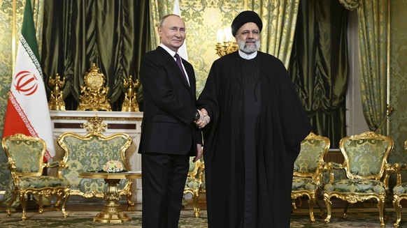 07.12.2023, Russland, Moskau: Auf diesem von der staatlichen russischen Nachrichtenagentur Sputnik via AP veröffentlichten Foto gibt Wladimir Putin (l), Präsident von Russland, Ebrahim Raisi, Präsiden ...