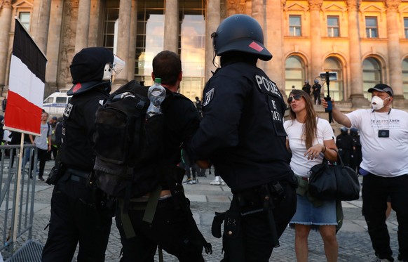 Police officers detain a protester in front of the Reichstag Building during a rally against the government's restrictions following the coronavirus disease (COVID-19) outbreak, in Berlin, Germany, Au ...