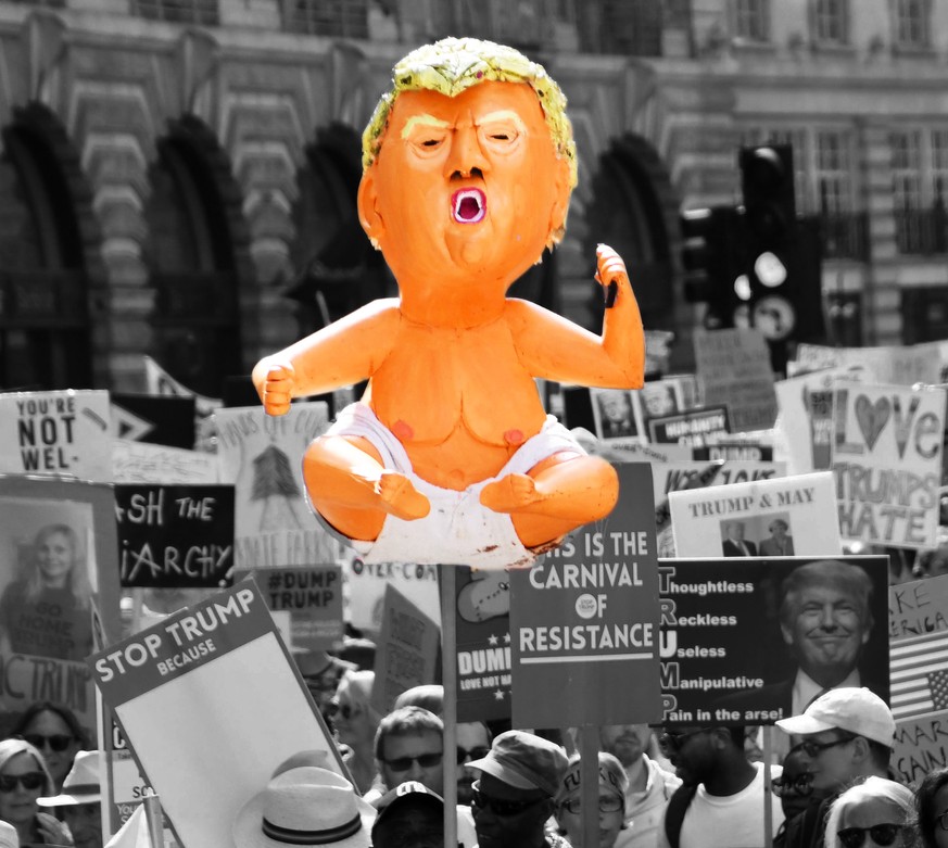 Protesters against the UK visit of US President Donald Trump hold signs and a baby Trump figure as they take part in a march and rally in London on July 13, 2018. Tens of thousands of protesters demon ...