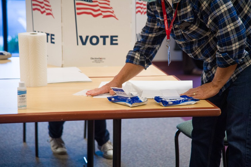 US-Wahl, Wahltag in Michigan SCIO TOWNSHIP, MI - NOVEMBER 03: An election official cleans tables and the ballot holders during voting at the polls for the 2020 Presidential Election in Scio Township,  ...