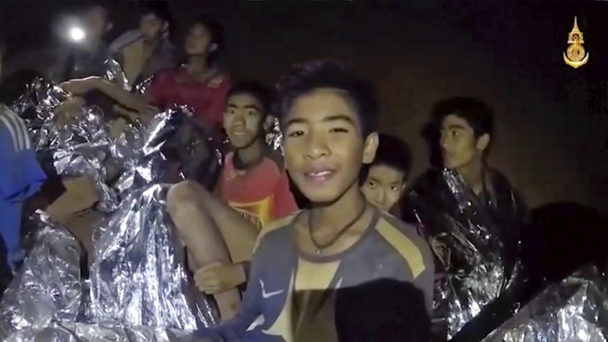 In this July 3, 2018, image taken from video provided by the Royal Thai Navy Facebook Page, Thai boys smile as Thai Navy SEAL medic help injured children inside a cave in Mae Sai, northern Thailand. T ...