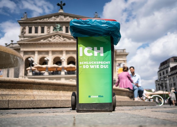 17.07.2020, Hessen, Frankfurt/Main: Eine Mülltonne mit der Aufschrift «Ich bin ein Schluckspecht - So wie Du» steht am Nachmittag auf dem Platz vor der Alten Oper (im Hintergrund) als Reaktion des stä ...