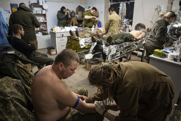 dpatopbilder - 26.02.2023, Ukraine, Bachmut: Ein ukrainischer Militärsanitäter behandelt einen verwundeten Kameraden in einem Feldlazarett in der Nähe von Bachmut. Foto: Evgeniy Maloletka/AP/dpa +++ d ...