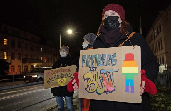 Eine Frau steht mit einem Schild in der Hand mit dem Text „Freiberg ist Bunt“ an der B173 in Freiberg. An diesem Abend läuft in der Stadt eine Kundgebung unter dem Motto &quot;Vernunft statt Angst&quo ...
