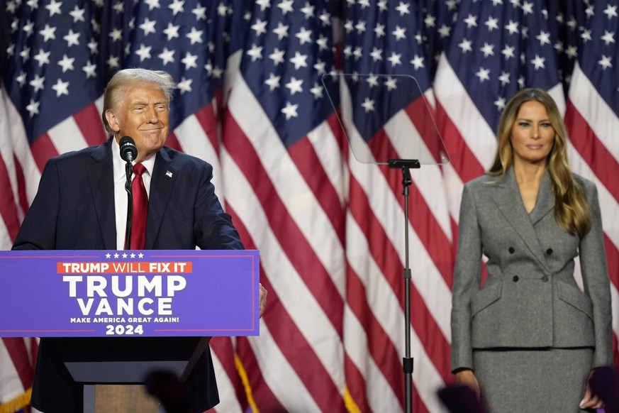 06.11.2024, USA, West Palm Beach: Der republikanische Präsidentschaftskandidat und ehemalige Präsident Donald Trump spricht, während Melania Trump bei einer Wahlparty am Mittwoch, 6. November 2024, in ...