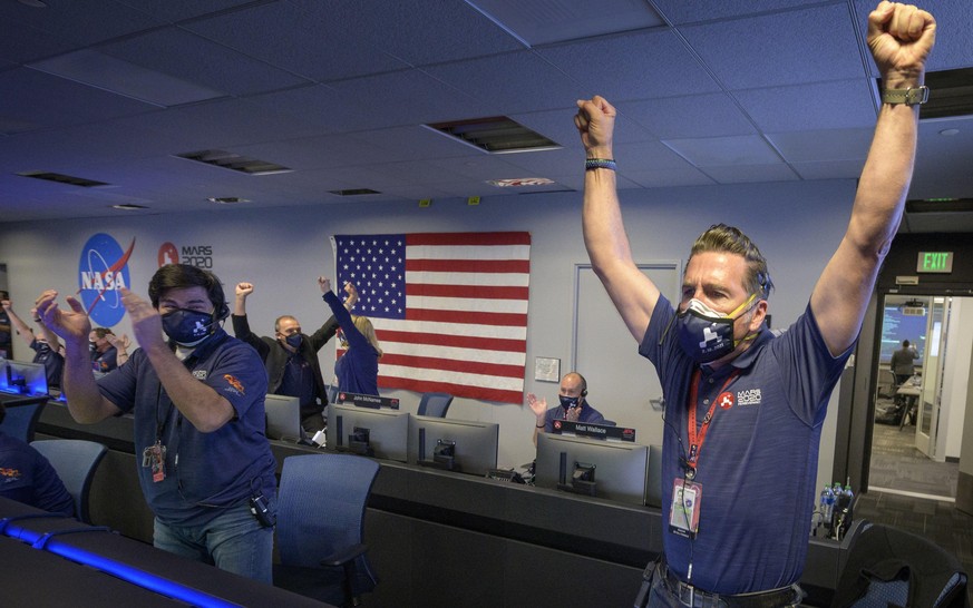 HANDOUT - 18.02.2021, USA, Pasadena: Mitarbeiter des Perseverance-Rover-Teams der NASA jubeln in der Missionskontrolle, nachdem sie die Best