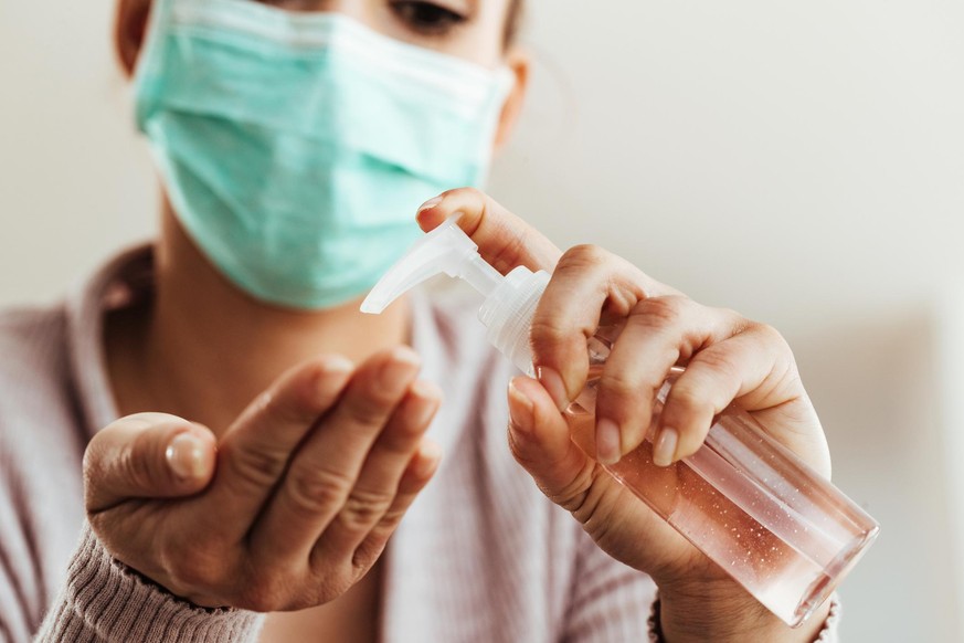 Close-up of woman using antibacterial hand gel at home.