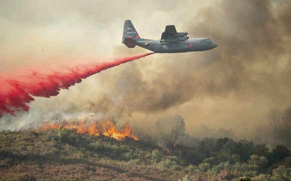 FILE - In this Sunday, Aug. 5, 2018, file photo, a U.S. Air Force plane drops fire retardant on a burning hillside in the Ranch Fire in Clearlake Oaks, Calif. Authorities say a rapidly expanding North ...