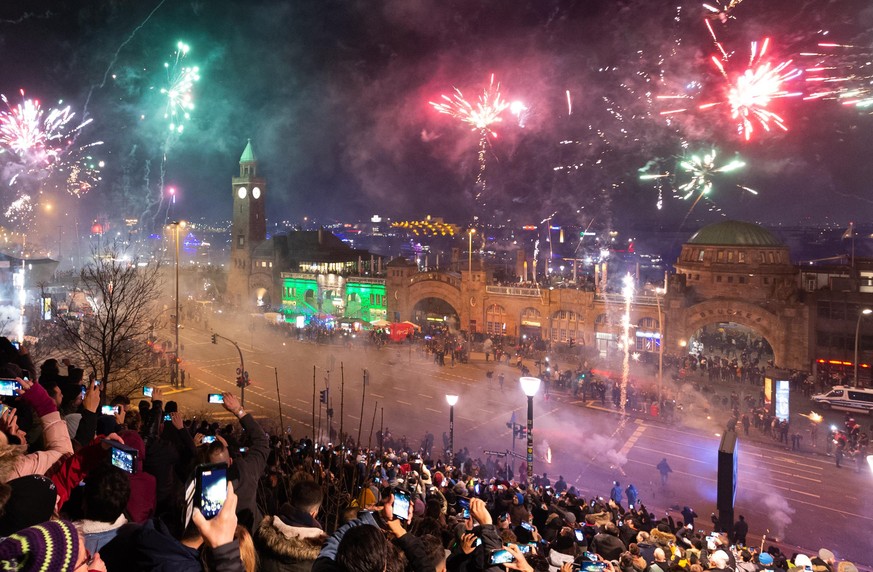 Schaulustige beobachten um Mitternacht das Feuerwerk an den Hamburger Landungsbrücken.