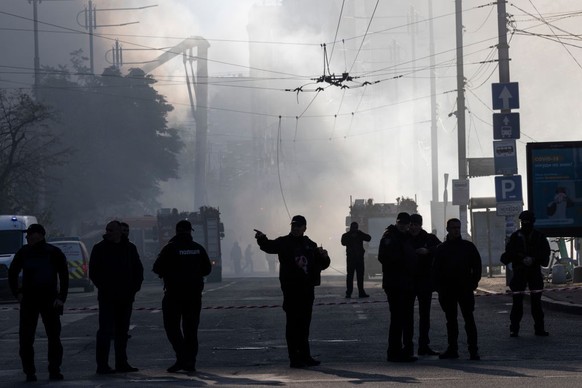 KYIV, UKRAINE - OCTOBER 17: Members of the Ukrainian police force stand guard next to smoke as Ukraine's capital is rocked by explosions during a drone attack in the early morning on October 17, 2022  ...