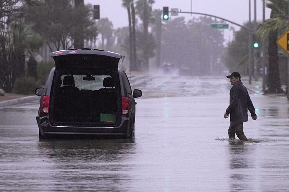 A motorist gets out of his vehicle after getting stuck in a flooded street, Sunday, Aug. 20, 2023, in Palm Desert, Calif.  Forecasters say Tropical Storm Hilary is the first ...