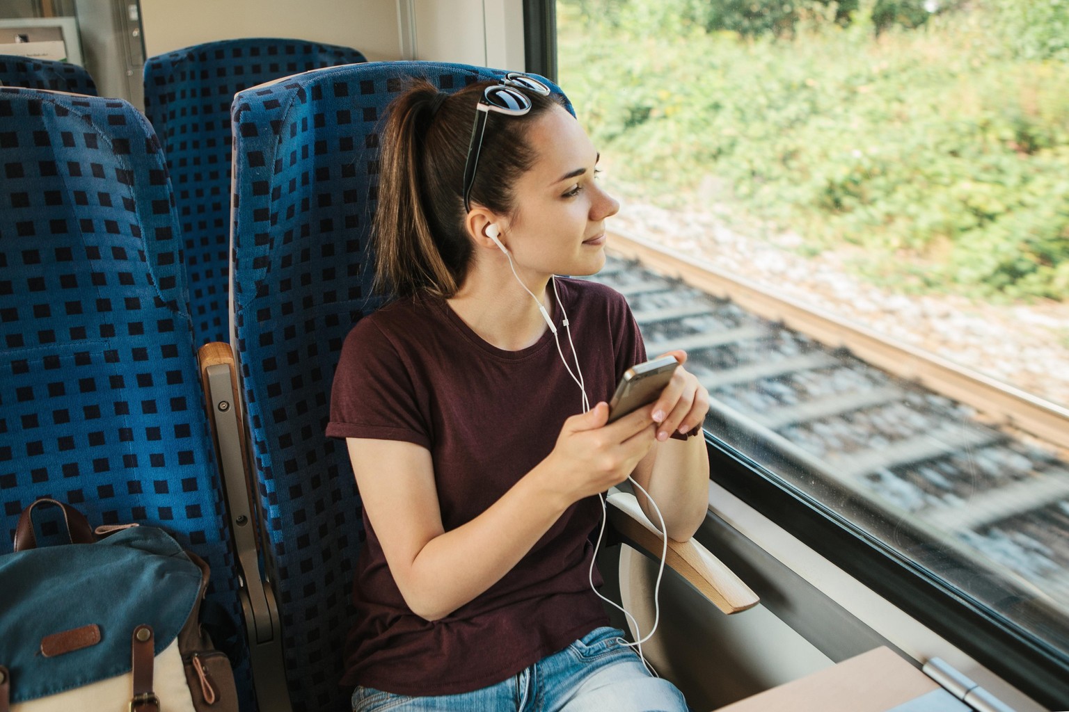 Eine Frau fährt Zug und schaut dabei aus dem Fenster.