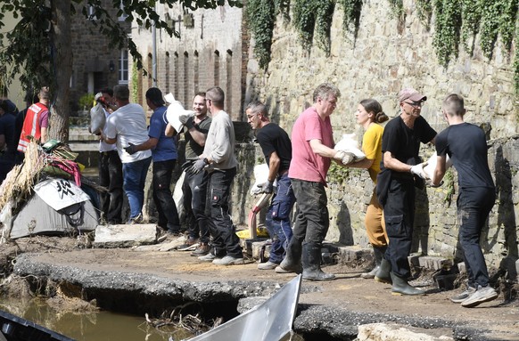 17.07.2021, Nordrhein-Westfalen, Bad Münstereifel: Mit einer Menschenkette befördern Helfer Sandsäcke in ein brüchiges Uferteil der Erft. In der Nacht zum 15.07.2021 verwüstete das Hochwasser der Erft ...