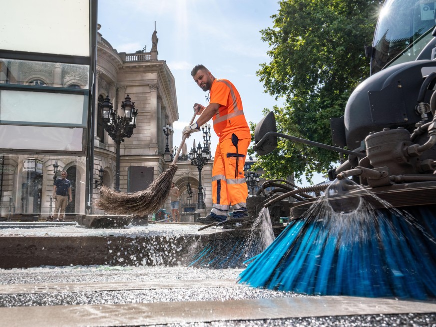 19.07.2020, Hessen, Frankfurt/Main: Mitarbeiter der Stadtreinigung beseitigen am Morgen vor der Alten Oper Scherben der zertrümmerten Scheiben einer Bushaltestelle. In der Nacht zum 19.07.2020 war es  ...