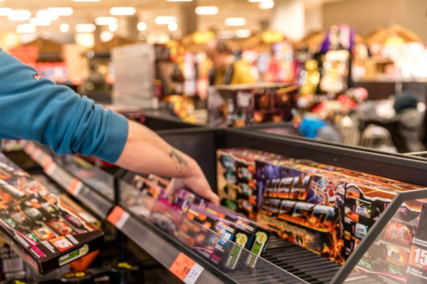 ARCHIV - 28.12.2023, Brandenburg, Cottbus: Ein Kunde eines Supermarktes nimmt Feuerwerk aus einem Regal. Am heutigen Tag beginnt der Verkauf von Silvesterfeuerwerk. Bis zum kommenden Samstag werden Bö ...