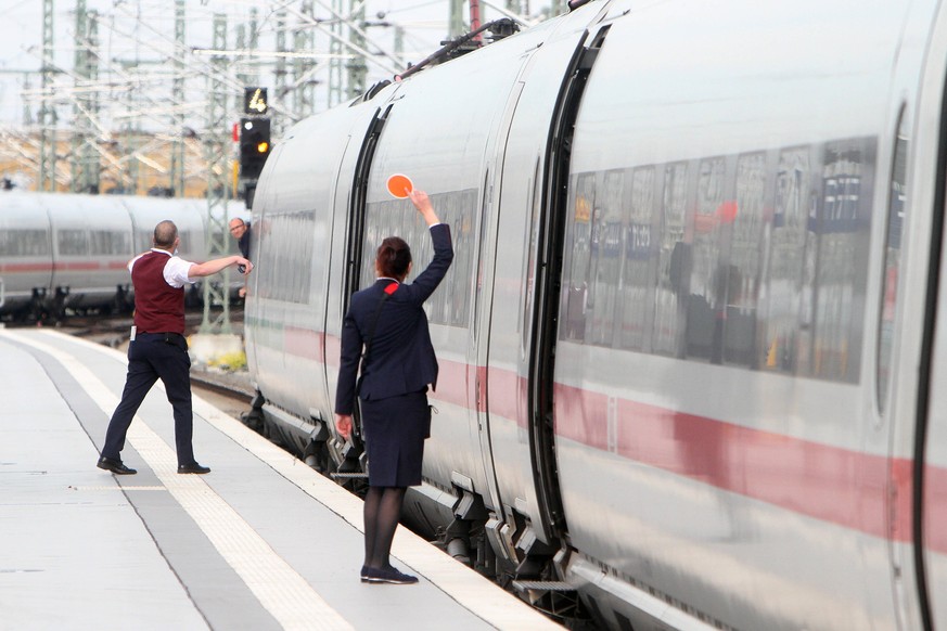 Zugbegleiter der DB Deutsche n Bahn AG signalisieren dem aus dem Fenster schauenden Lokf