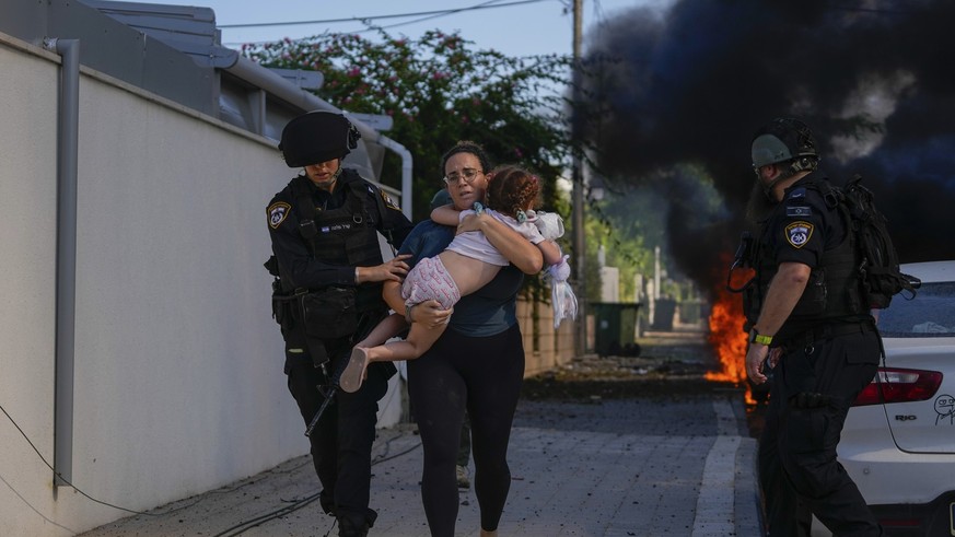 07.10.2023, Israel, Ashkelon: Israelische Polizei evakuieren eine Frau und ein Kind von einem Ort, der von einer aus dem Gazastreifen abgefeuerten Rakete getroffen wurde. Nach massiven Angriffen aus d ...