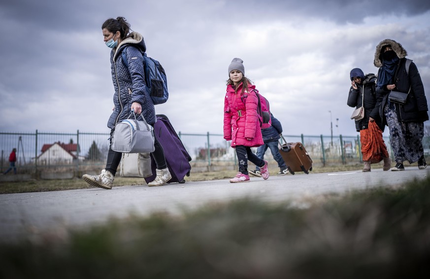 Geflüchtete aus der Ukraine gehen nach ihrem Grenzübertritt in Polen durch das polnische Grenzgebiet. Zahlreiche Menschen verlassen nach dem Angriff Russlands auf die Ukraine das Land. Viele flüchten  ...