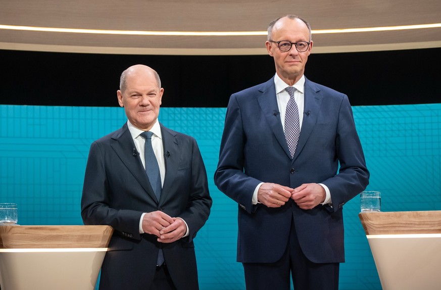 ARCHIV - 09.02.2025, Berlin: Bundeskanzler Olaf Scholz (SPD, l), steht neben Friedrich Merz, Unions Kanzlerkandidat und CDU Bundesvorsitzender, vor dem TV-Duell von ARD und ZDF. In 90 Minuten stellen  ...