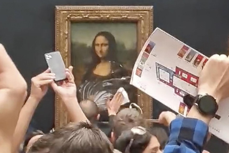 A security guard cleans smeared cream from the glass protecting the Mona Lisa at the Louvre Museum, in Paris, France, Sunday, May 29, 2022. A man seemingly disguised as an old woman in a wheelchair th ...
