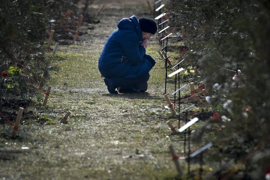 FILE - The mother of a Russian soldier who was killed in a military action in Ukraine, kneels near a planted tree in memory of her son at the Alley of Heroes in Sevastopol, Crimea, Saturday, Feb. 25,  ...