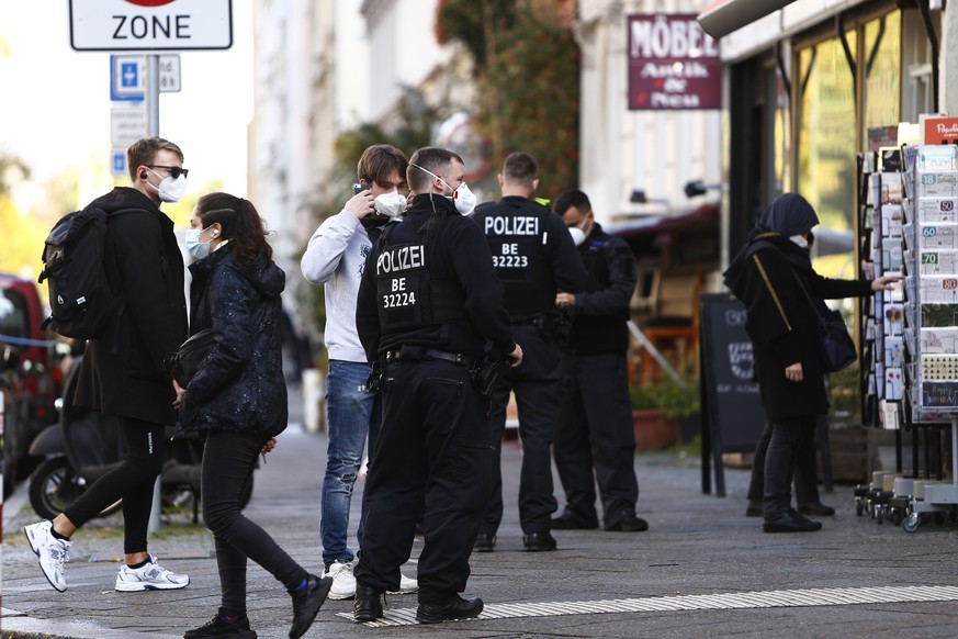 BERLIN, GERMANY - OCTOBER 24: Policemen patrol along the Bergmanstrasse, one the main shopping street in Kreuzberg district, on the first day that a requirement by city authorities that people wear ma ...