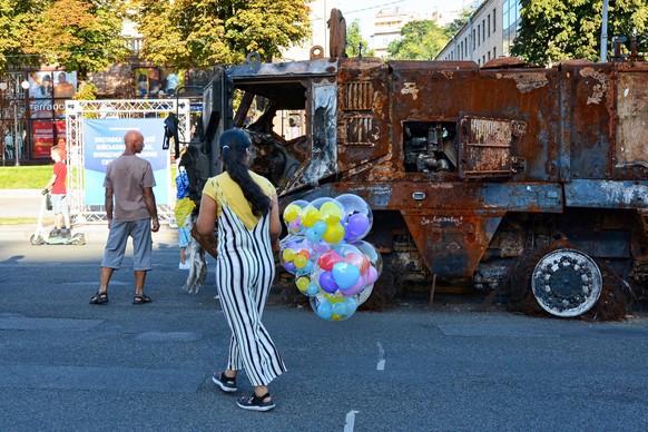 August 24, 2022, Kyiv, Ukraine: A woman with balloons observes the destroyed Russian army equipment displayed at Khreshchatyk in the center of Kyiv. Captured Russian military equipment is being tempor ...