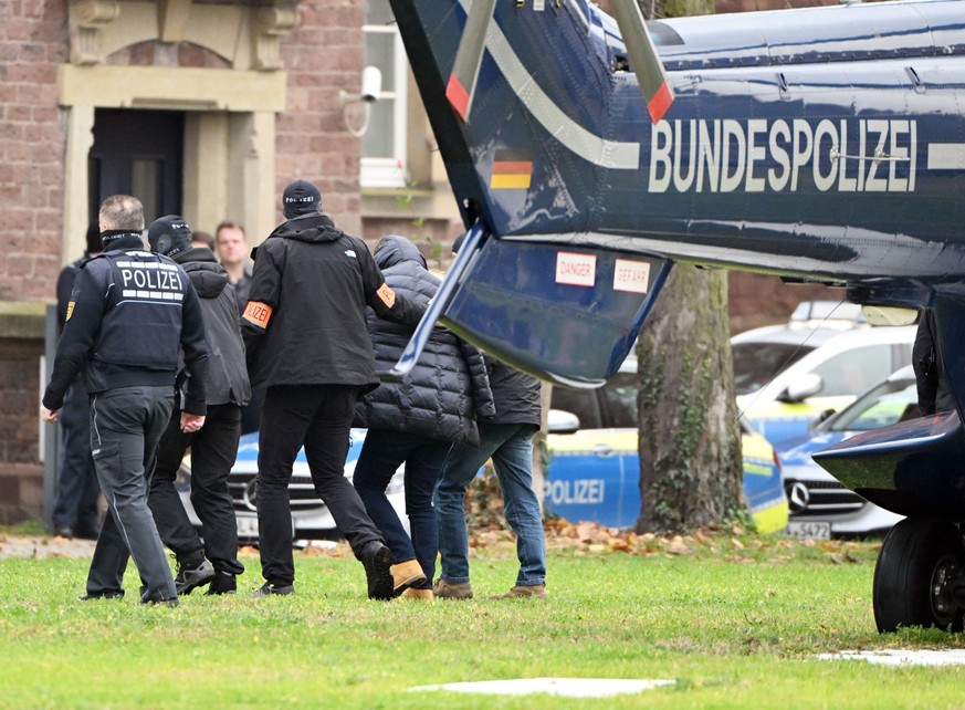 07.12.2022, Baden-Württemberg, Karlsruhe: Eine Person (2.v.r.) wird von Polizisten aus einem Hubschrauber gebracht. Die Bundesanwaltschaft hat am Mittwochmorgen mehrere Menschen aus der sogenannten &q ...