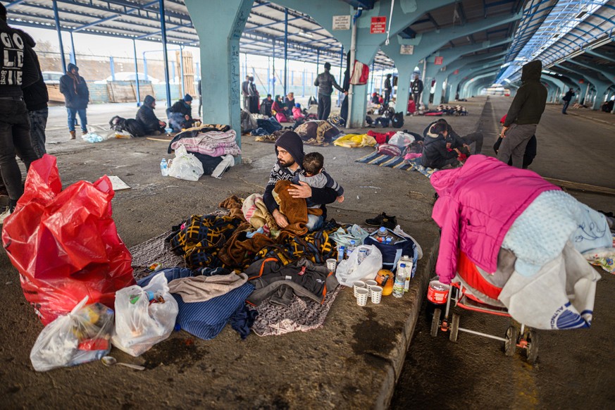 Ein Syrer sitzt während seiner Flucht in der türkischen Grenzstadt Edirne nähe des Grenzübergangs Pazarkule-Kastanies in einer leeren Markthalle und hält sein Kind in seinen Armen.