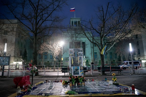 24.02.2023, Berlin: Vor der russischen Botschaft Unter den Linden sind Blumen und eine Wand mit Fotos aufgestellt, als Erinnerung an den russischen Angriffskrieg auf die Ukraine vor einem Jahr. Die ru ...
