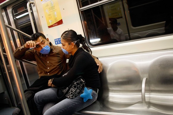 Menschen schützen sich mit Atemschutz-Hauben gegen einen Schweinegrippe-Ausbruch in Mexiko im Jahr 2009.