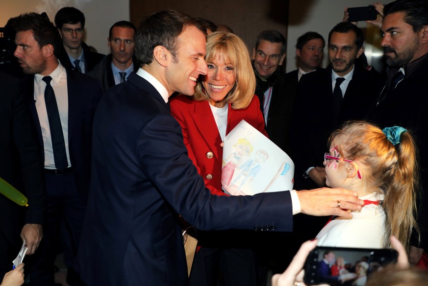 French President Emmanuel Macron and his wife Brigitte Macron receive a drawing as a present from a girl during the Christmas Party for the children of Elysee Palace's employees at the Gobelins Manufa ...
