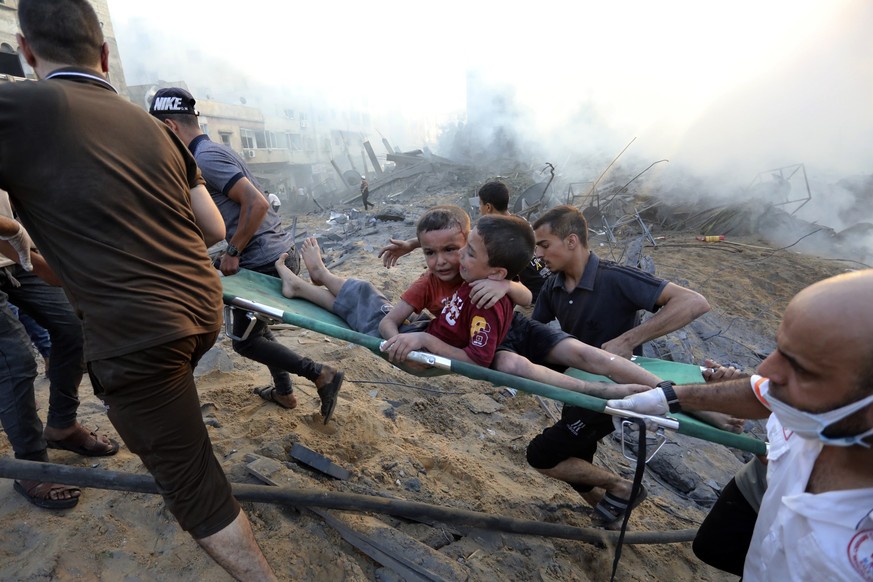 Palestinians evacuate two wounded boys out of the destruction following Israeli airstrikes on Gaza City, Wednesday, Oct. 25, 2023. Hundreds of thousands of Palestinians have decided to stay in their h ...