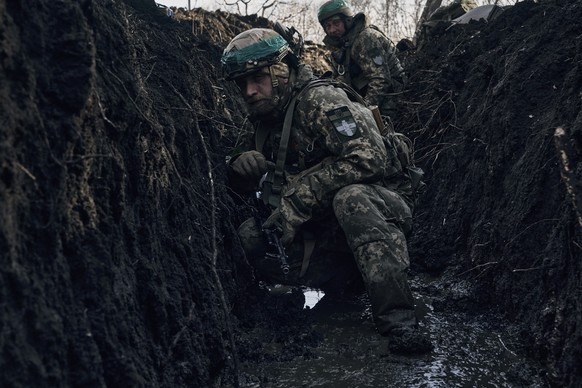 05.03.2023, Ukraine, Bachmut: Ukrainische Soldaten kauern in einem Schützengraben unter russischem Beschuss an der Frontlinie in der Nähe von Bachmut. Foto: LIBKOS/AP/dpa +++ dpa-Bildfunk +++