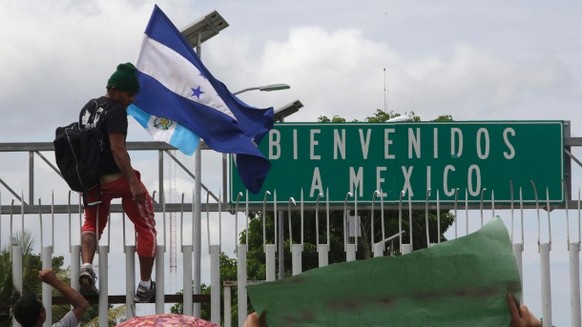 Ein
junger Mann ist mit der Flagge von Honduras auf den Grenzzaun zwischen
Guatemala und Mexiko geklettert.