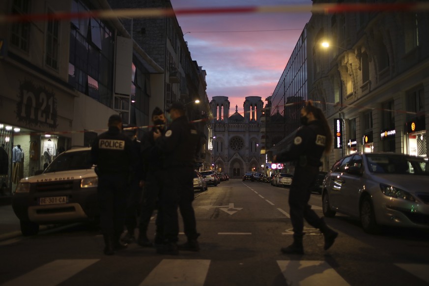 29.10.2020, Frankreich, Nizza: Polizisten gehen unter einem Absperrband vor der Kirche Notre Dame nach einem Messerangriff durch. Bei der Messerattacke hat es mindestens drei Tote und mehrere Verletzt ...