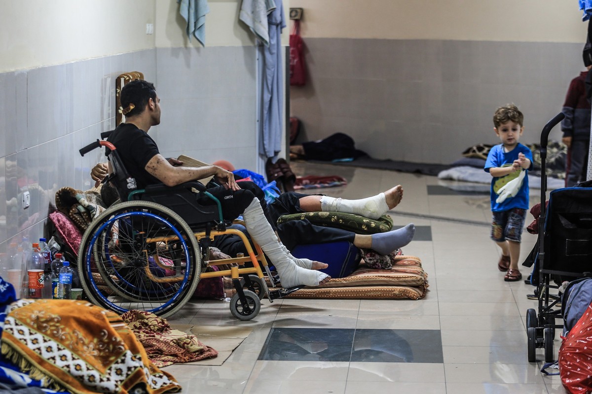 13.11.2023, Palästinensische Gebiete, Chan Junis: Atef Al-Helou (M) aus dem Viertel Shujaiya in der Stadt Gaza hält sich mit seinen Angehörigen im Nasser-Krankenhaus auf. Atef leidet an Brüchen in sei ...
