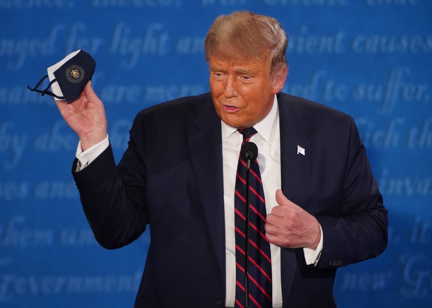 President Donald Trump holds up a face mask during the first of three scheduled 90-minute presidential debates with Democratic presidential nominee Joe Biden, in Cleveland, Ohio, on Tuesday, September ...