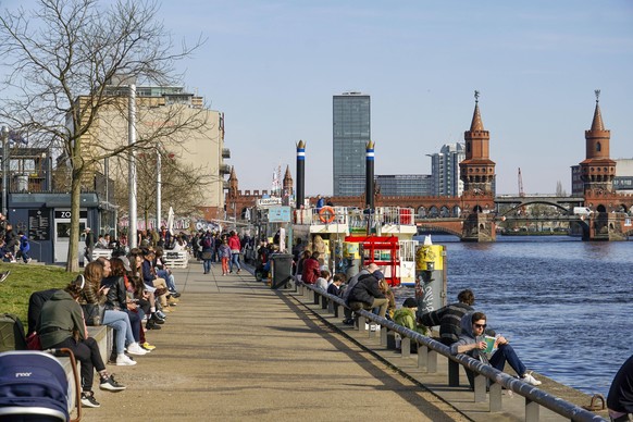 Menschen genießen das gute Wetter am Spreeufer in Berlin.