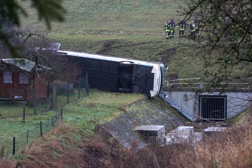 Rettungskräfte stehen neben einem verunglückten Schulbus. Bei Eisenach in Thüringen verunglückte am Morgen auf eisglatter Straße ein Schulbus.