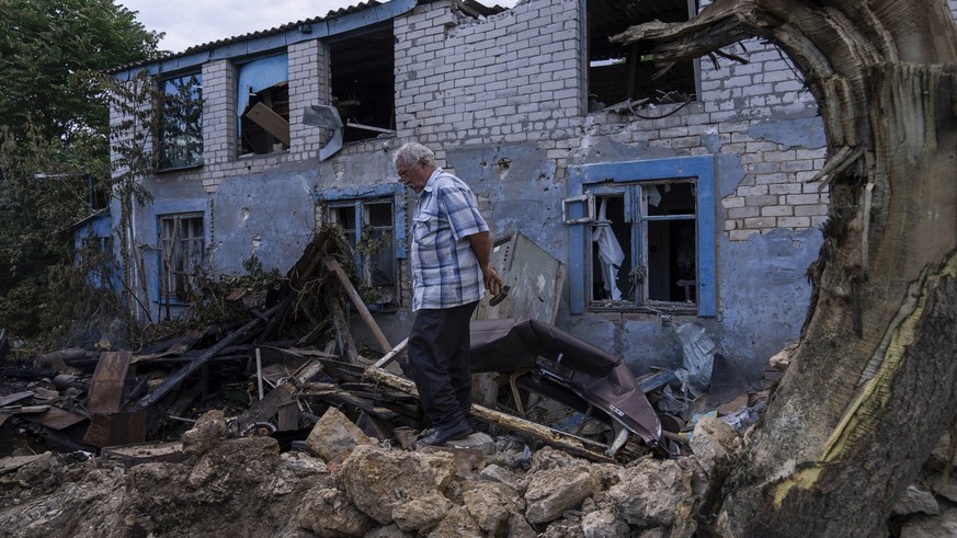 29.06.2023, Ukraine, Cherson: Ein Einheimischer geht vor einem durch russischen Beschuss beschädigten Gebäude in Cherson. In der südukrainischen Stadt Cherson sind am 29.06.2023 nach Angaben lokaler B ...