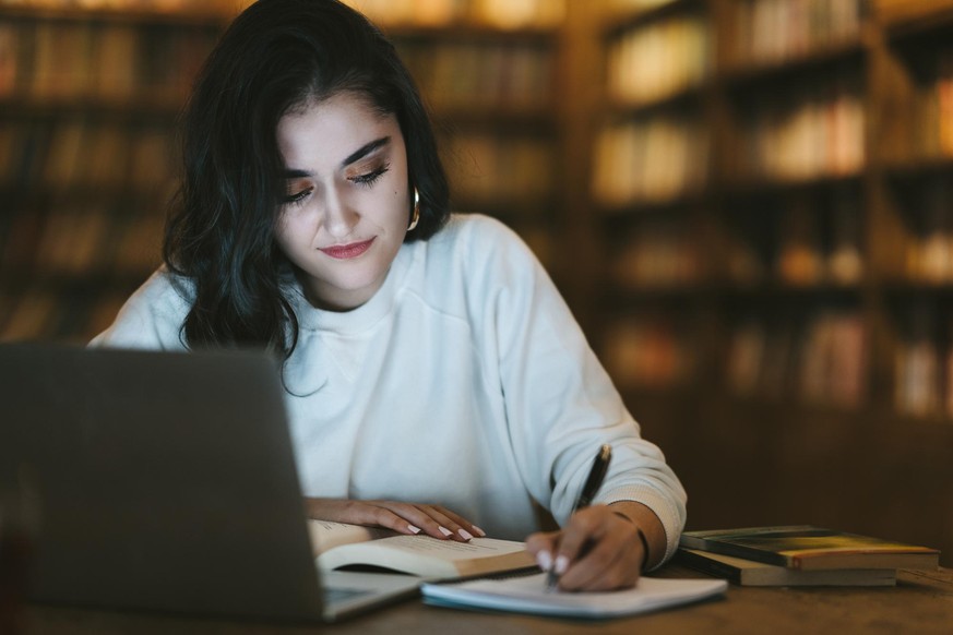 A young college student is studying on laptop in a cafe.