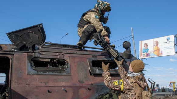 Ukrainische Soldaten inspizieren ein beschädigtes Militärfahrzeug nach Kämpfen in Charkiw.