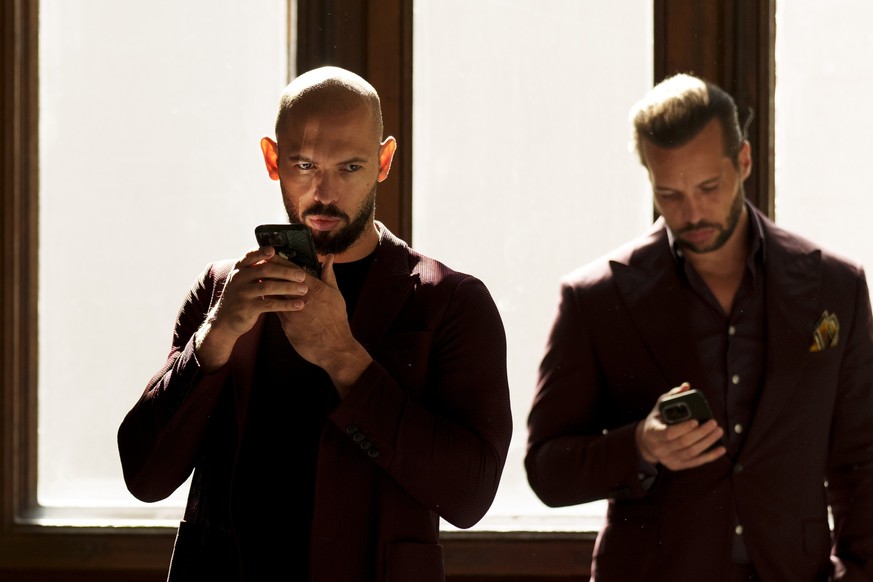 Andrew Tate, left, and his brother Tristan, right, wait at the Court of Appeals building in Bucharest, Romania, Tuesday, Oct. 15, 2024. (AP Photo/Vadim Ghirda)