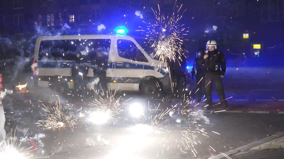 31.12.2022, Berlin: Polizeibeamte stehen hinter explodierendem Feuerwerk. Nach Angriffen auf Einsatzkr�fte in der Silvesternacht hat die Diskussion um Konsequenzen begonnen. Berlins Regierende B�rgerm ...