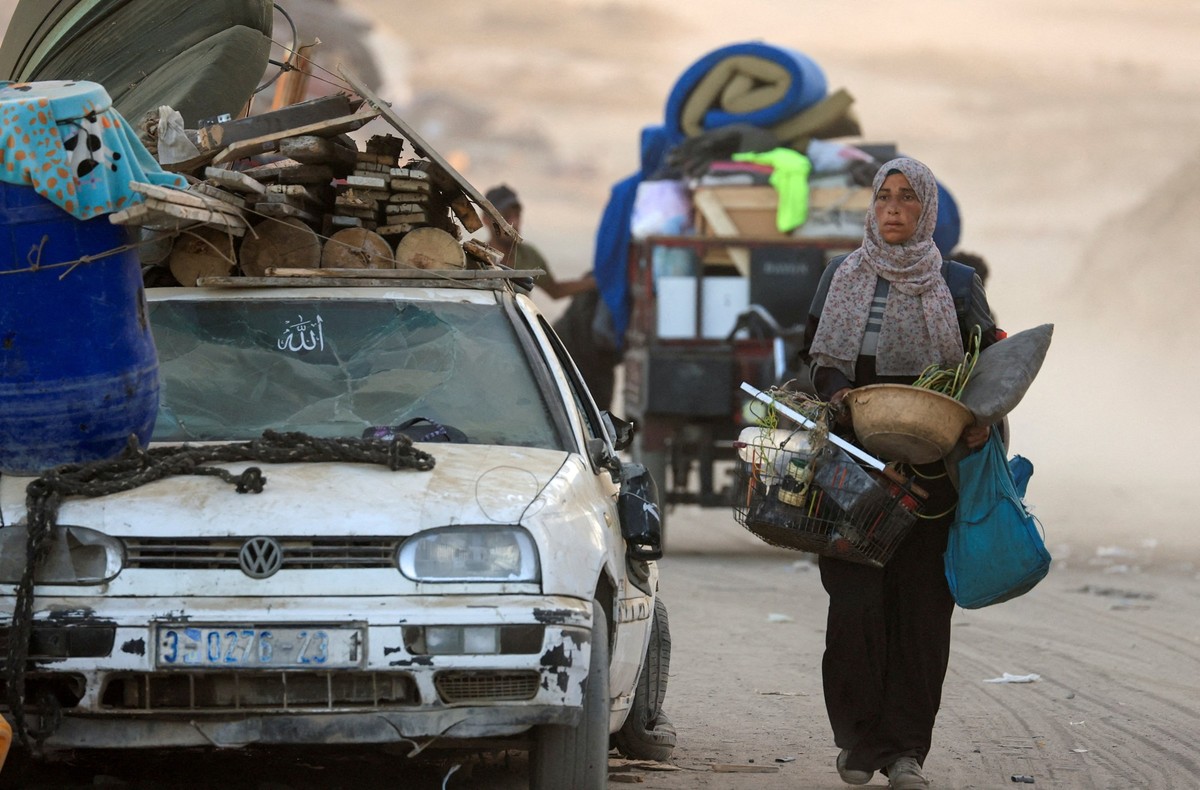 A displaced Palestinian woman, fleeing northern Gaza due to an Israeli military operation, carries belongings as she moves southwards after Israeli forces ordered residents of Gaza City to evacuate to ...