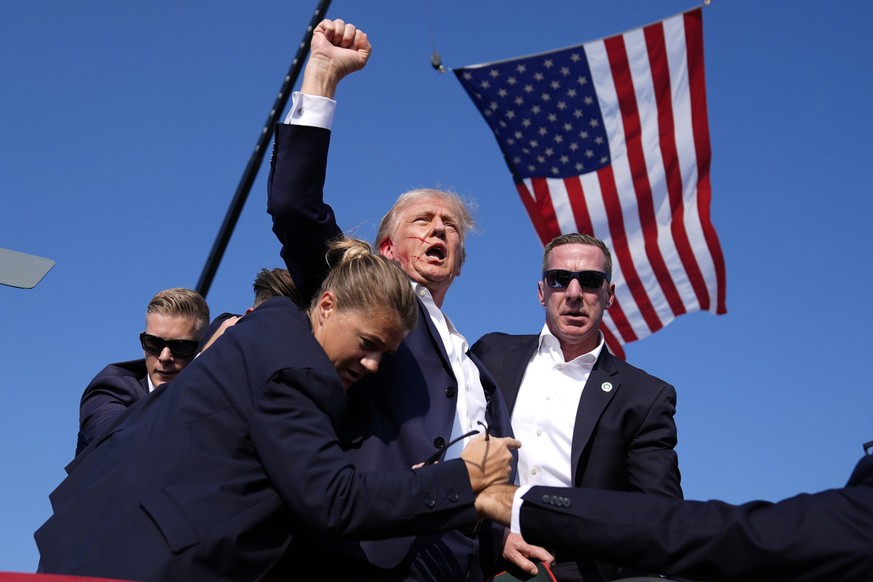 dpatopbilder - 13.07.2024, USA, Butler: Der republikanische Präsidentschaftsbewerber und ehemalige Präsident Donald Trump wird bei einer Wahlkampfveranstaltung in Butler, Pennsylvania, von Agenten des ...