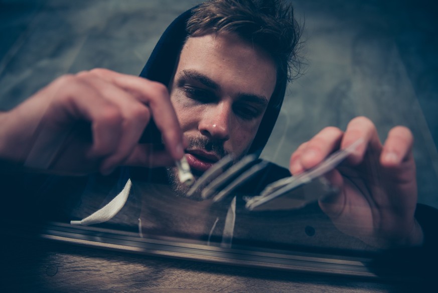Social problem among teenagers people youngsters concept. Low angle close up view photo portrait of sad desperate troubled unhappy exhausted guy snorting lines of crack on table using rolled bill